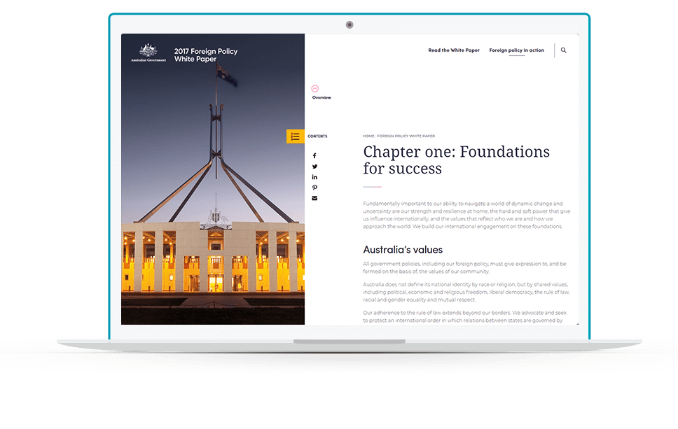 A hand holds a smartphone displaying an article titled \Foreign Policy in Practice\ beside a 2017 Foreign Policy White Paper on a table.